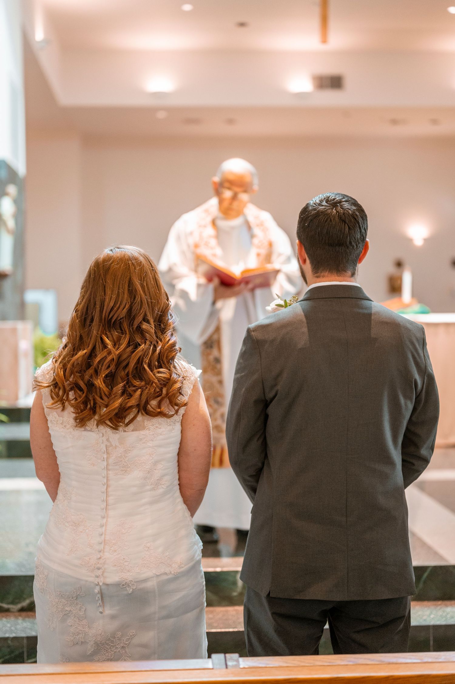 A couple stands at an altar while a minister conducts a wedding ceremony in an indoor venue.