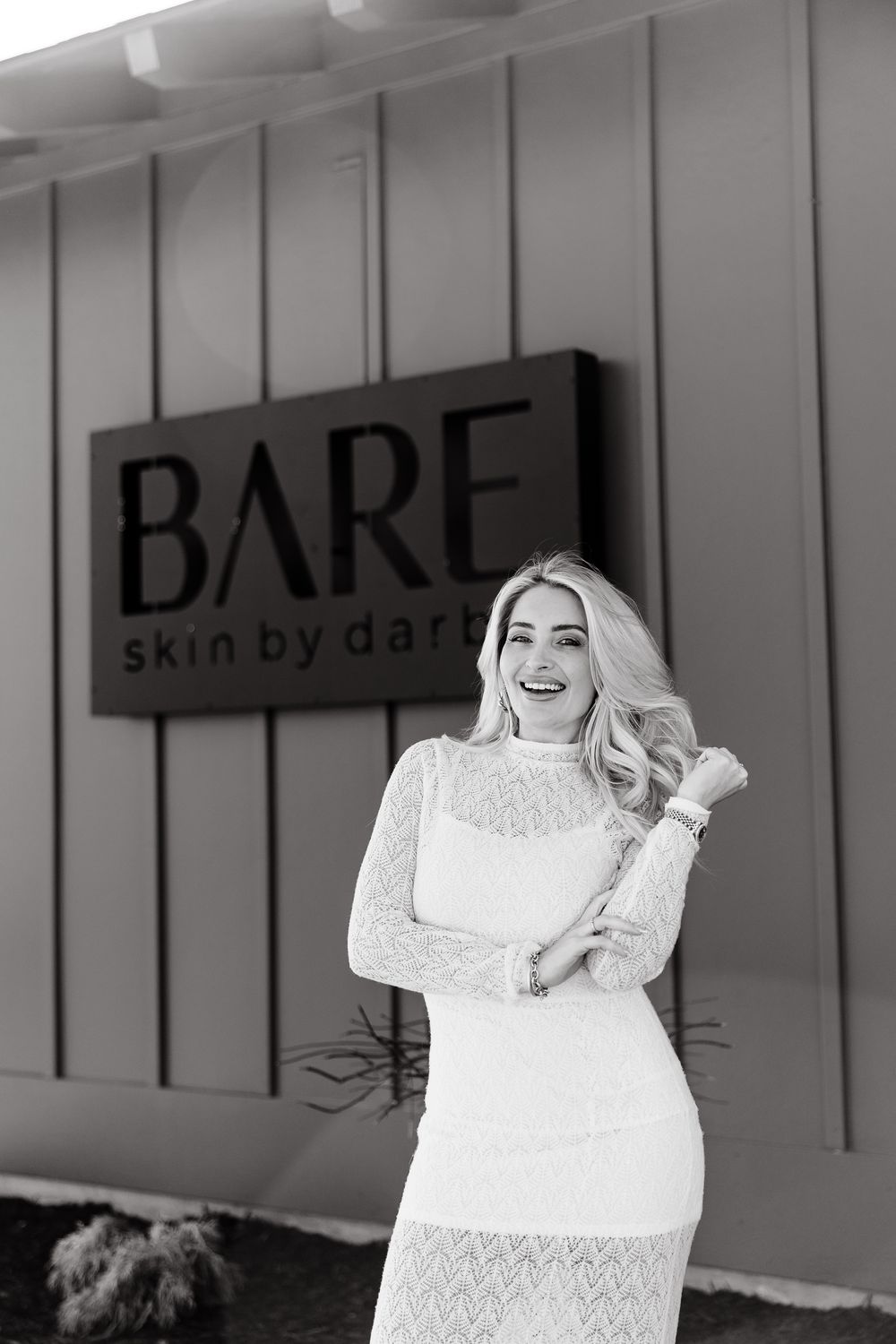 A black and white photo series showing a person in white lace dress posing expressively against a wall.