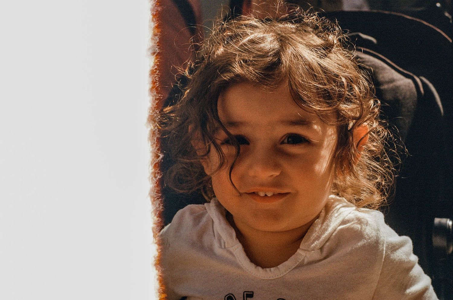 Portrait of someone with curly hair in soft natural lighting.