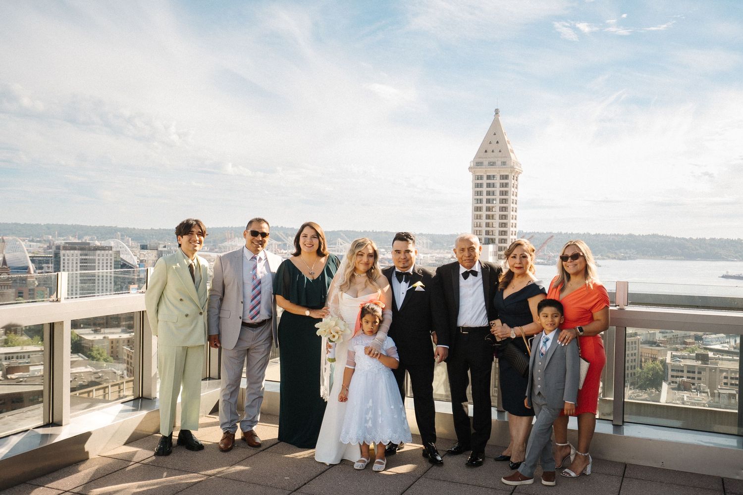 A group stands on a rooftop deck overlooking Seattle's skyline with Smith Tower visible in the background.