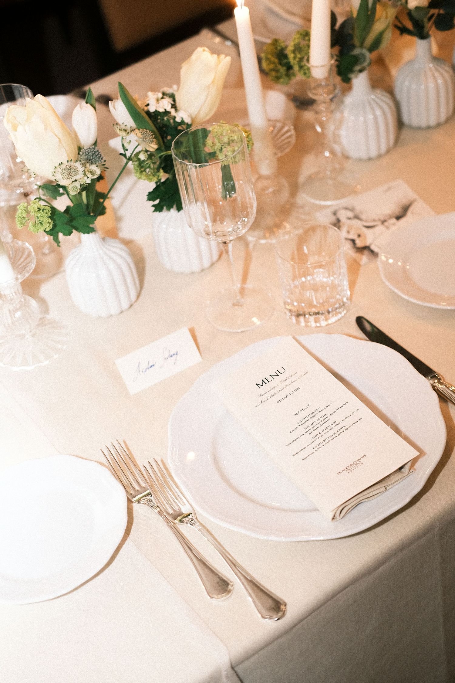 Elegant table setting with white tulips, candles and menu card.