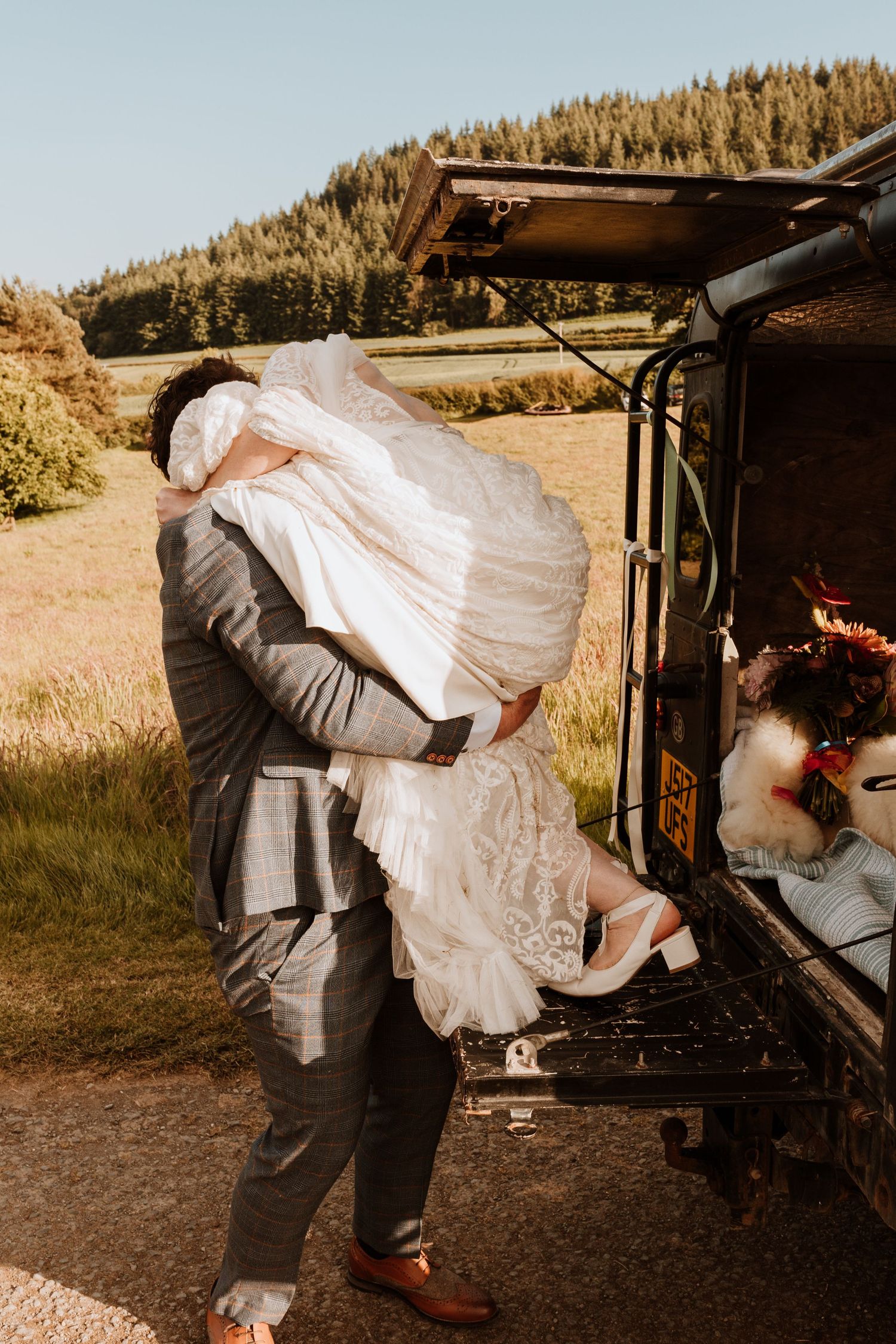 A sequence of wedding dress photos shows someone placing a gown into a vehicle trunk outdoors against a wooded backdrop.