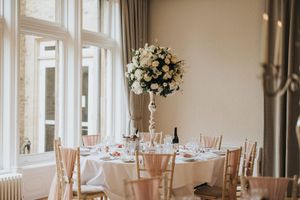 An elegant wedding reception venue decorated in white and blush tones with round tables and floral centrepieces at Cave Castle.