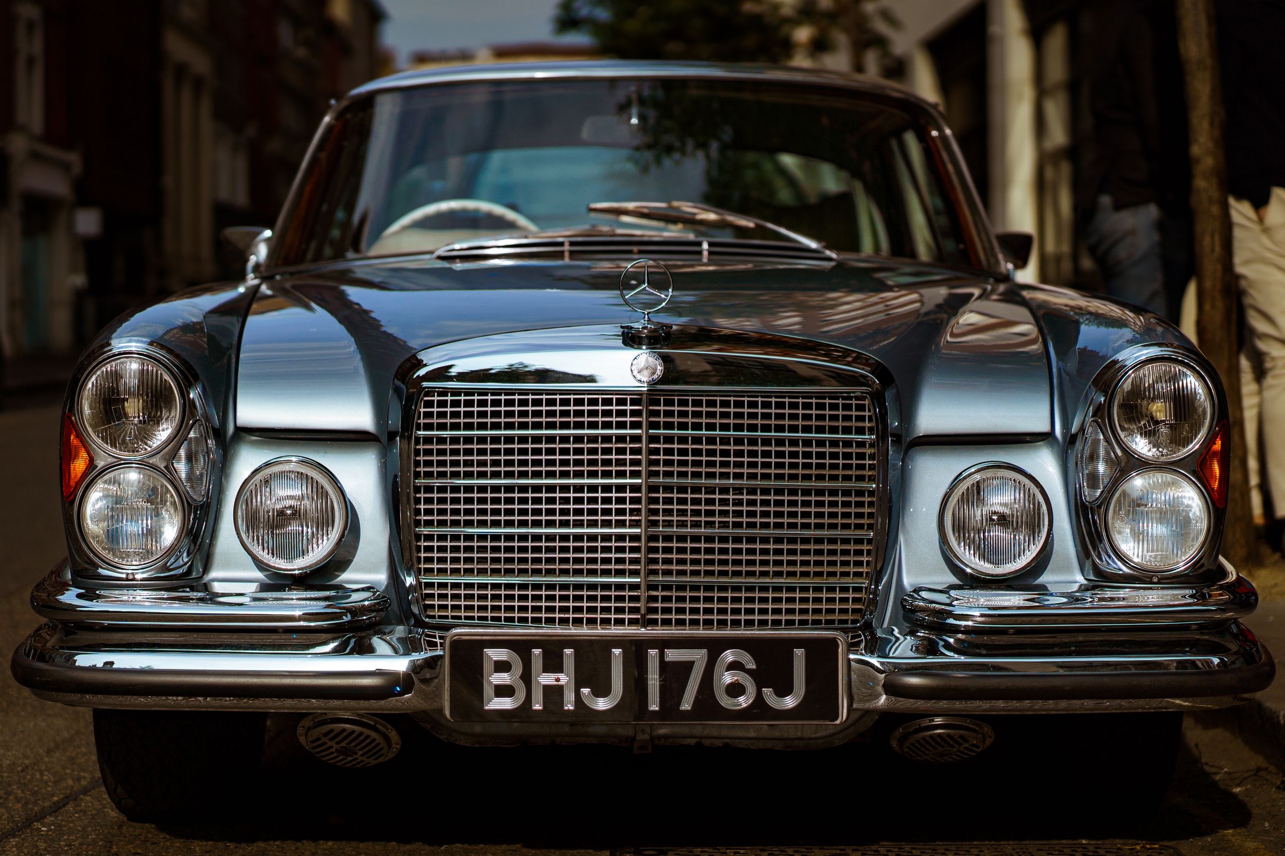 The front of a metallic sky blue vintage Mercedes car with a large grille