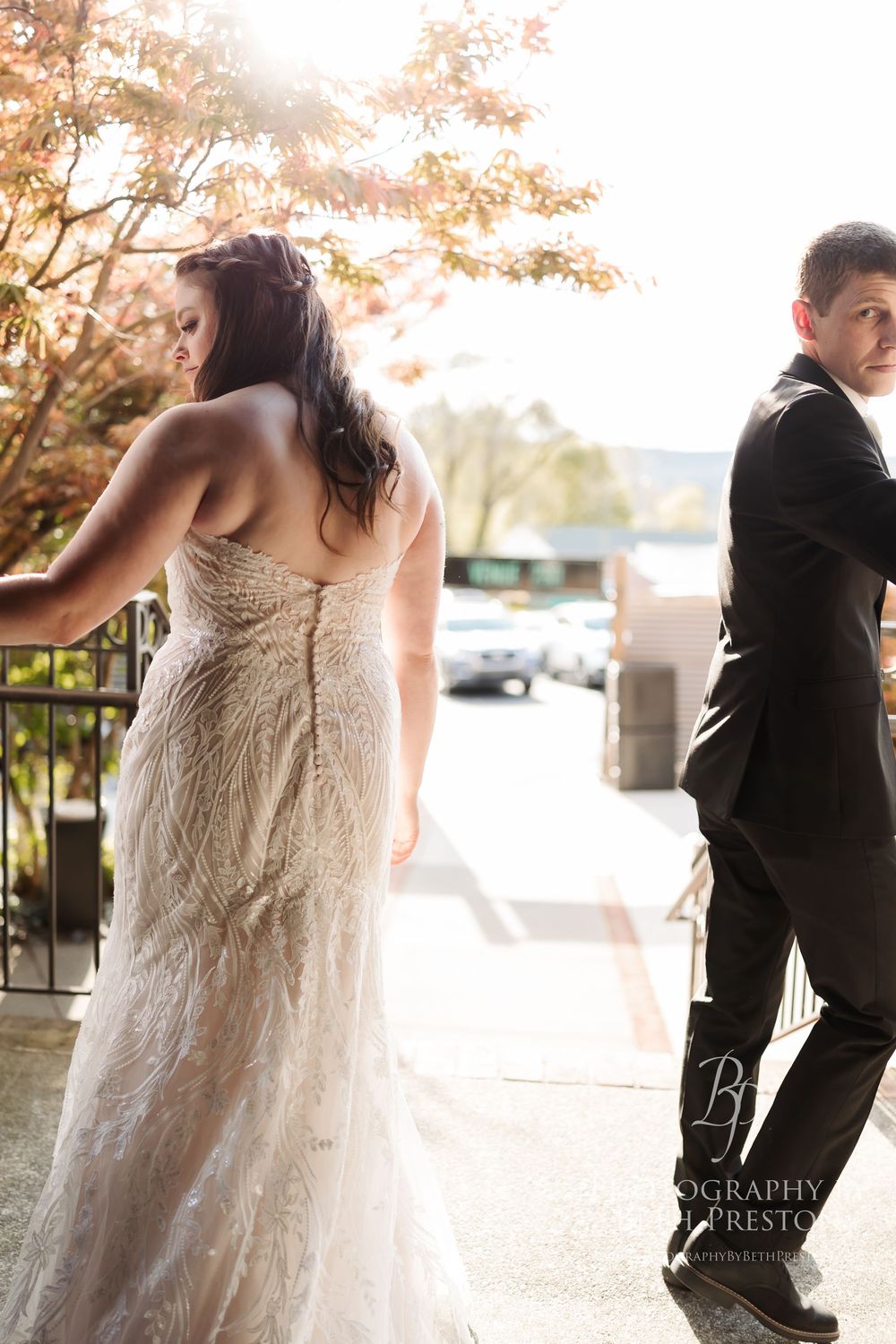 Romantic bride and groom embrace during sunset golden hour photoshoot at an elegant outdoor venue.