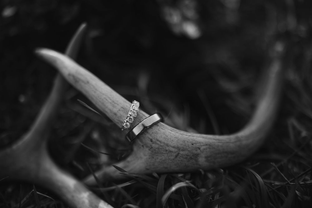 Black and white close-up photo of a hunting knife resting on an antler against a dark background.