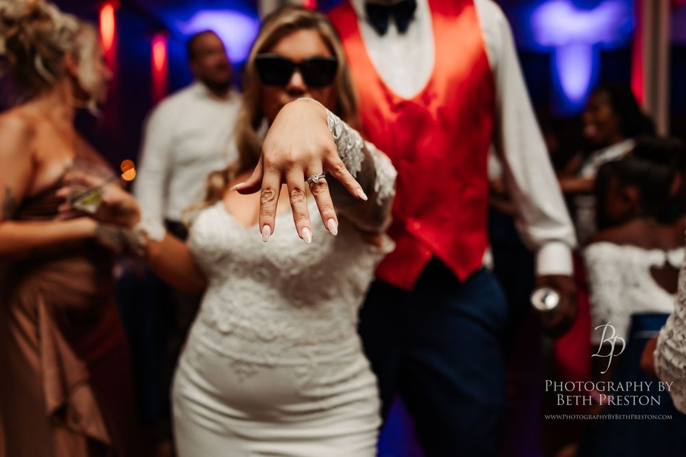 Wedding reception dance floor with couples dancing in formal attire under blue and red lighting.