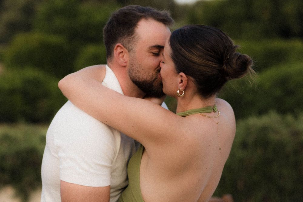 A tender moment captured at an outdoor wedding as a couple shares a romantic kiss.