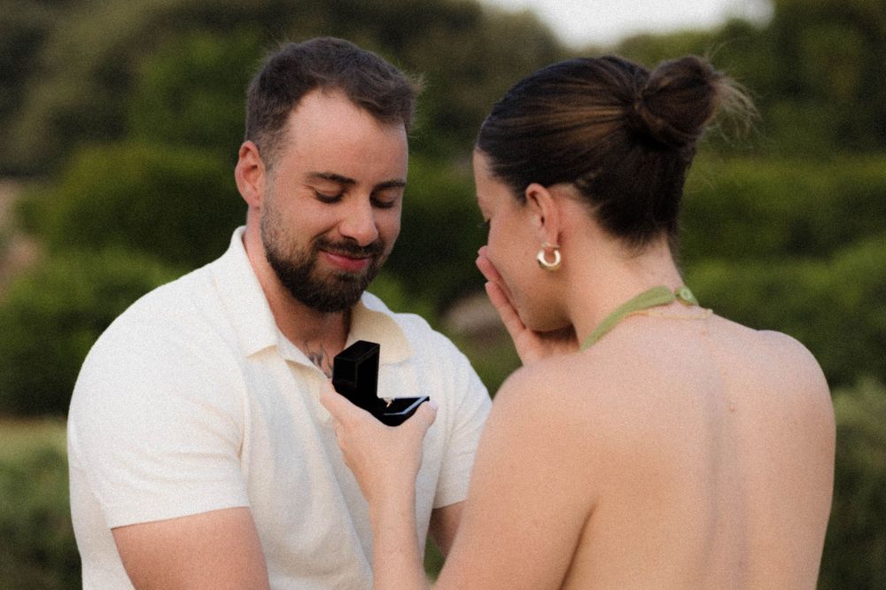 A couple shares an intimate moment at an outdoor wedding while wearing white attire.