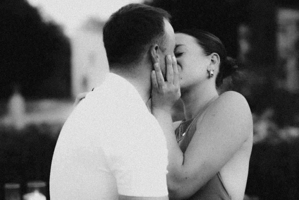 A romantic black and white photograph showing a close-up profile of a couple sharing a tender kiss.