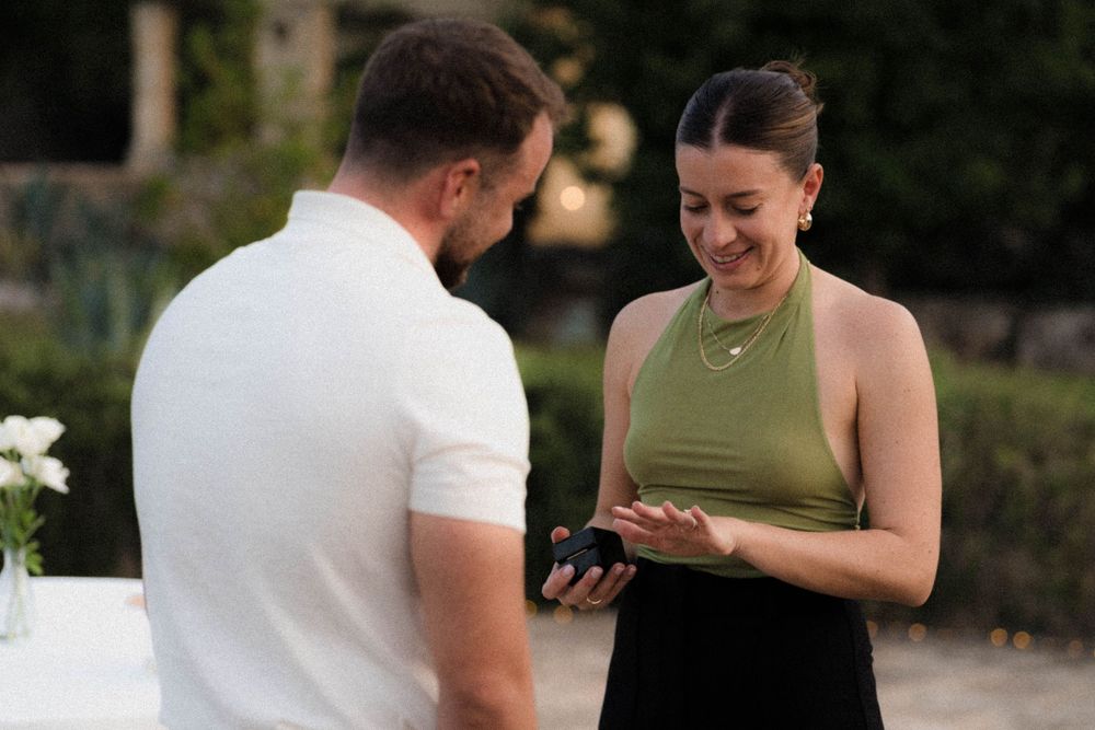 Two people dressed in black and white standing at an outdoor table having a joyful interaction.