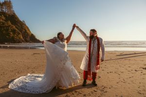 Golden hour wedding portraits on rugged Pacific Northwest beach with bride's dress trailing in sand.