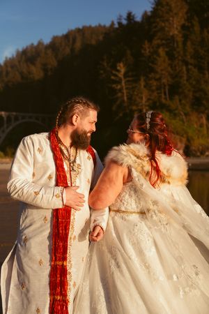 A couple in matching white outfits and red accents share tender moments during a sunset photo session.