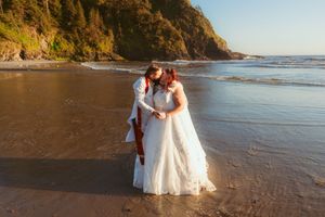 A romantic sunset beach wedding moment with waves crashing against the shore behind the couple.