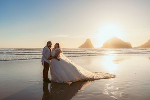 Two figures walk along a scenic beach at sunset as waves gently roll onto the shore behind them.