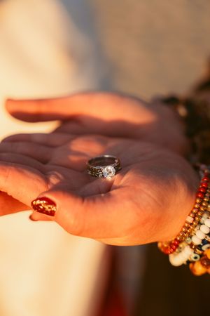 Close-up of ornate ring and colorful beaded bracelets in warm sunlight.