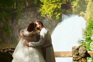 A romantic moment captured near a majestic waterfall surrounded by lush greenery.