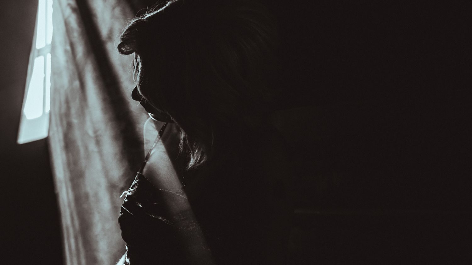 Ethereal portrait with soft natural lighting and bokeh through foliage in monochrome.
