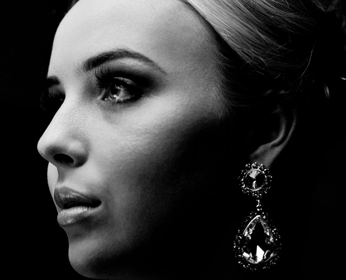 Artistic black and white profile portrait showing elegant crystal earrings and dramatic lighting.