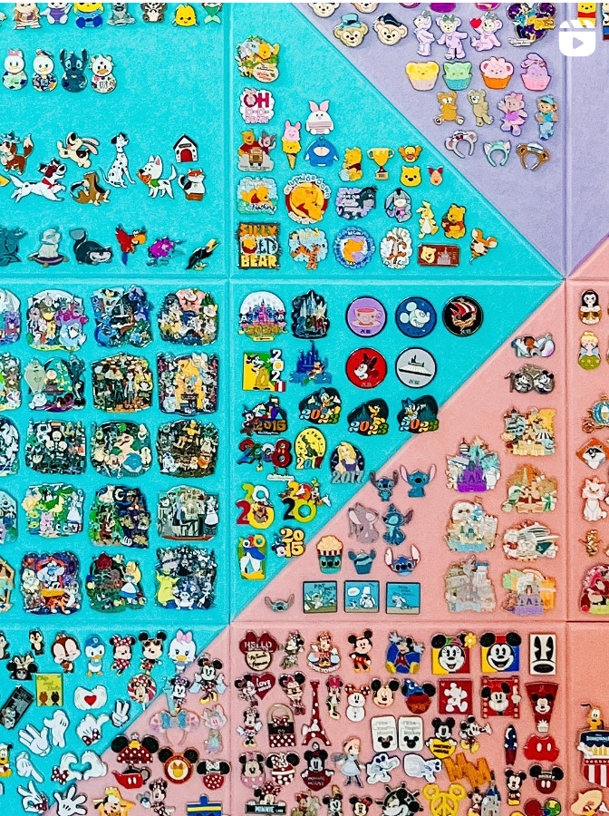 A colorful collection of Disney trading pins displayed on a turquoise background featuring various characters and designs.