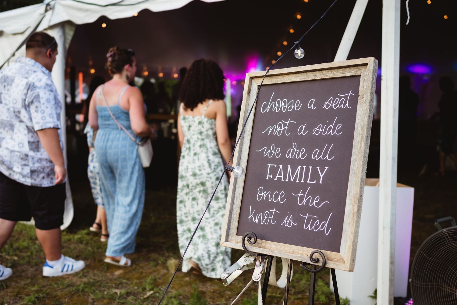 A rustic wedding chalkboard sign displays 'Family' among other handwritten text with twinkle lights in the background.