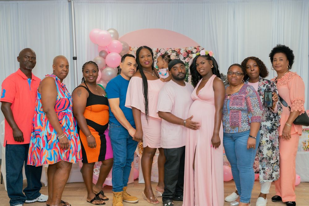A group of people pose together at a formal event wearing colorful dresses and outfits in pink, blue and orange tones.