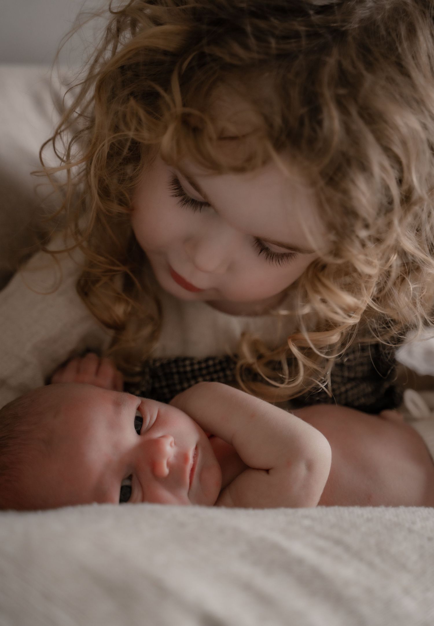 Parents cuddling their baby in soft morning light during an at-home newborn photoshoot in Leicestershire.