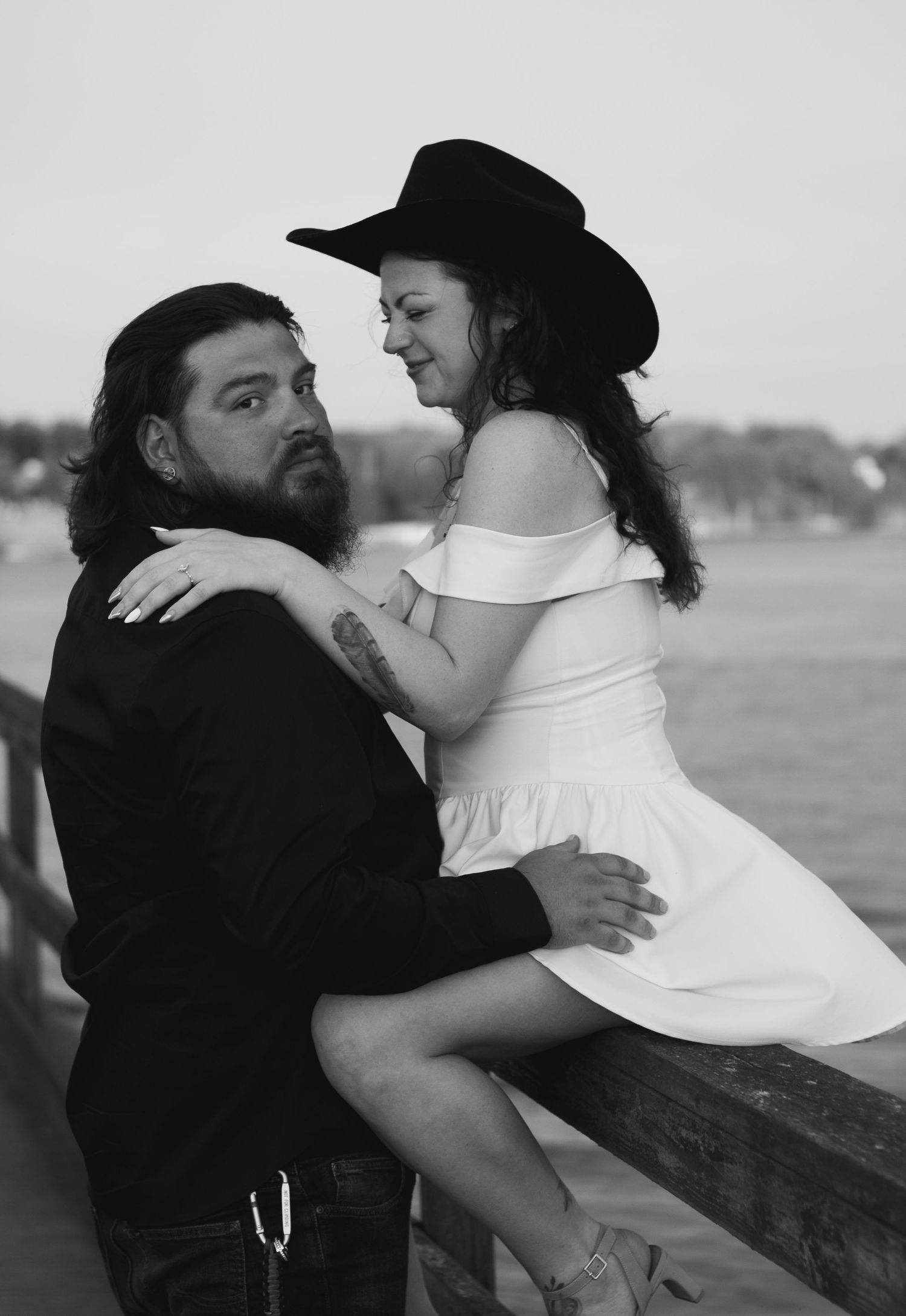Romantic black and white photo series showing couple embracing against a fence in five sequential poses.