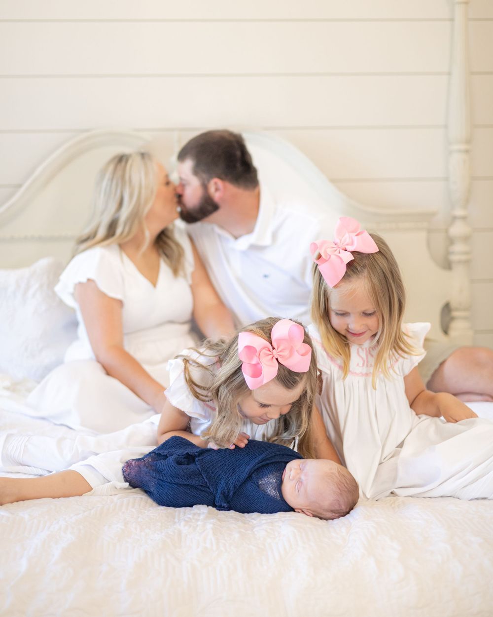 Family members relaxing together on white bedding wearing coordinated outfits.