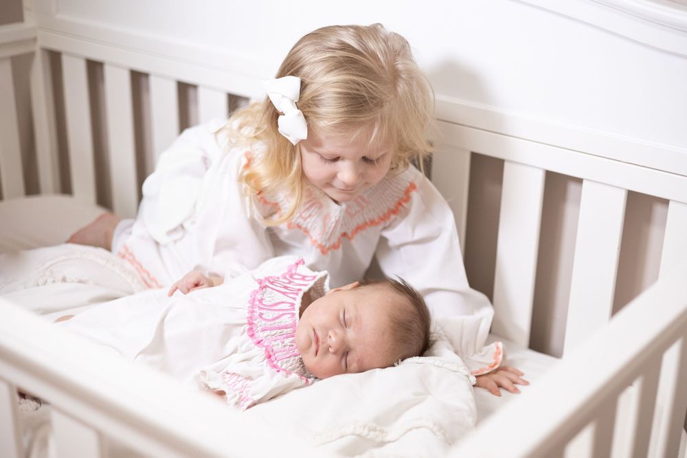 Sweet family moment captured in soft lighting on white bedding.