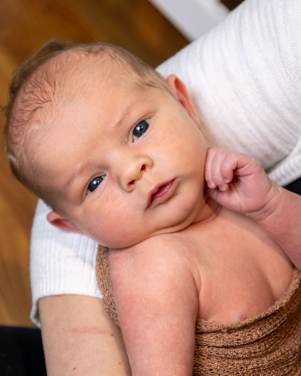 Newborn wrapped in brown textile photographed from multiple angles on white background.