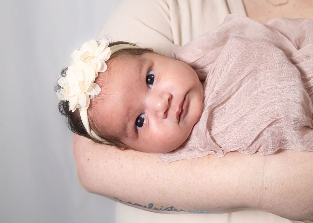 Baby in soft pink clothing lying on light colored background.