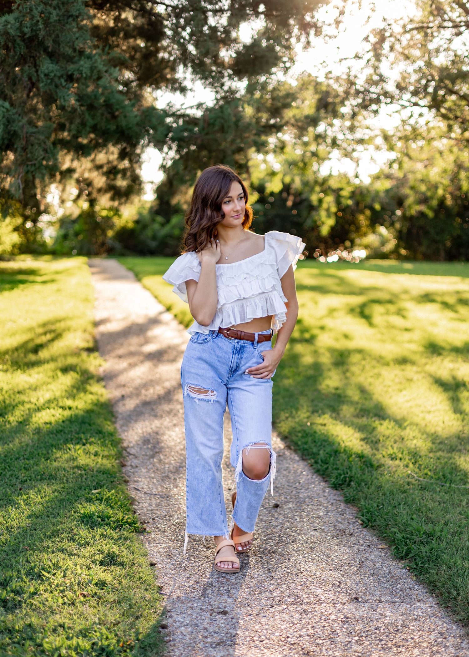 Casual outdoor portraits on gravel path wearing distressed denim and white top.