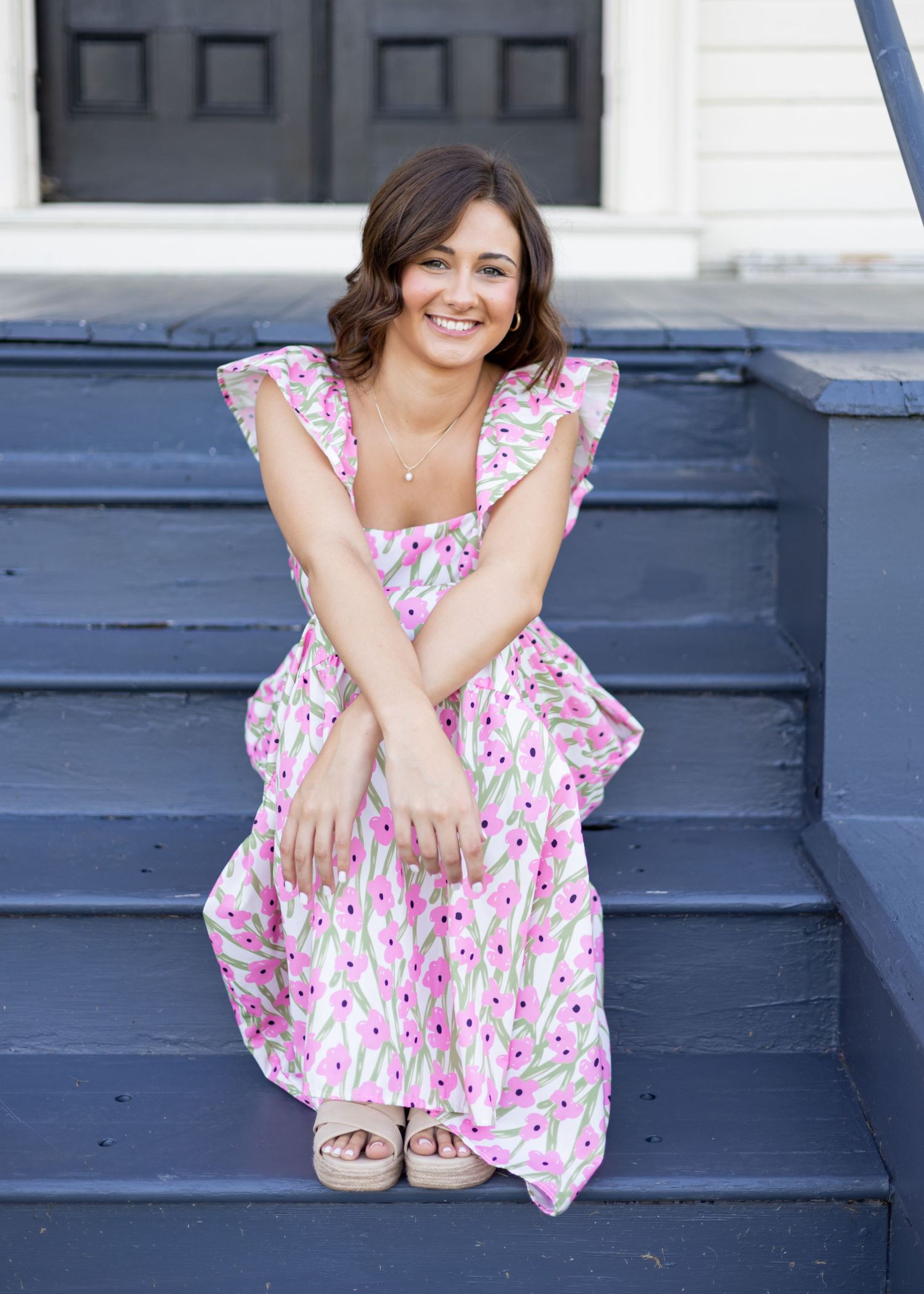 Stylish portraits on blue painted steps wearing floral summer dress.