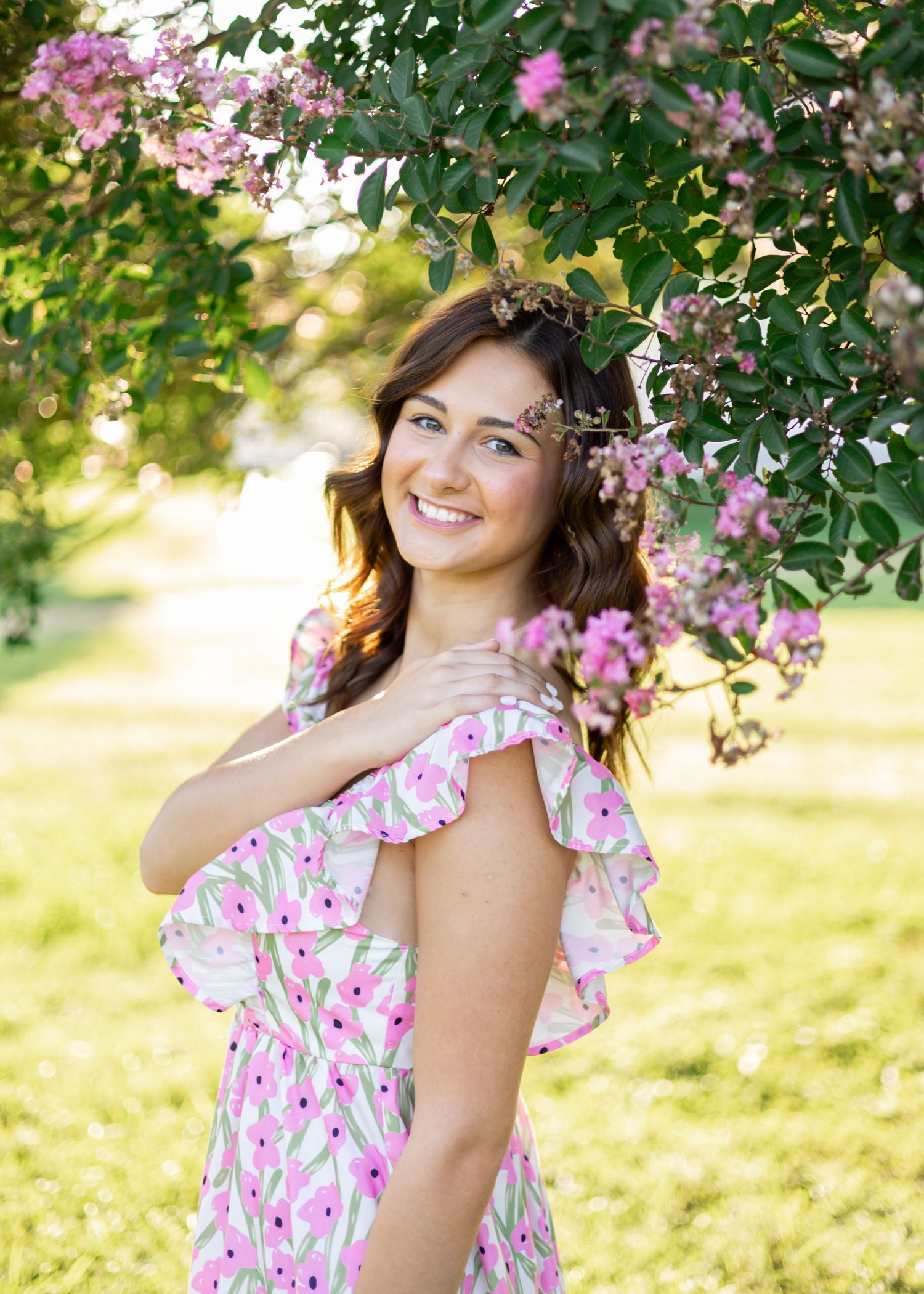 Summer fashion shoot under flowering trees in pink floral dress.