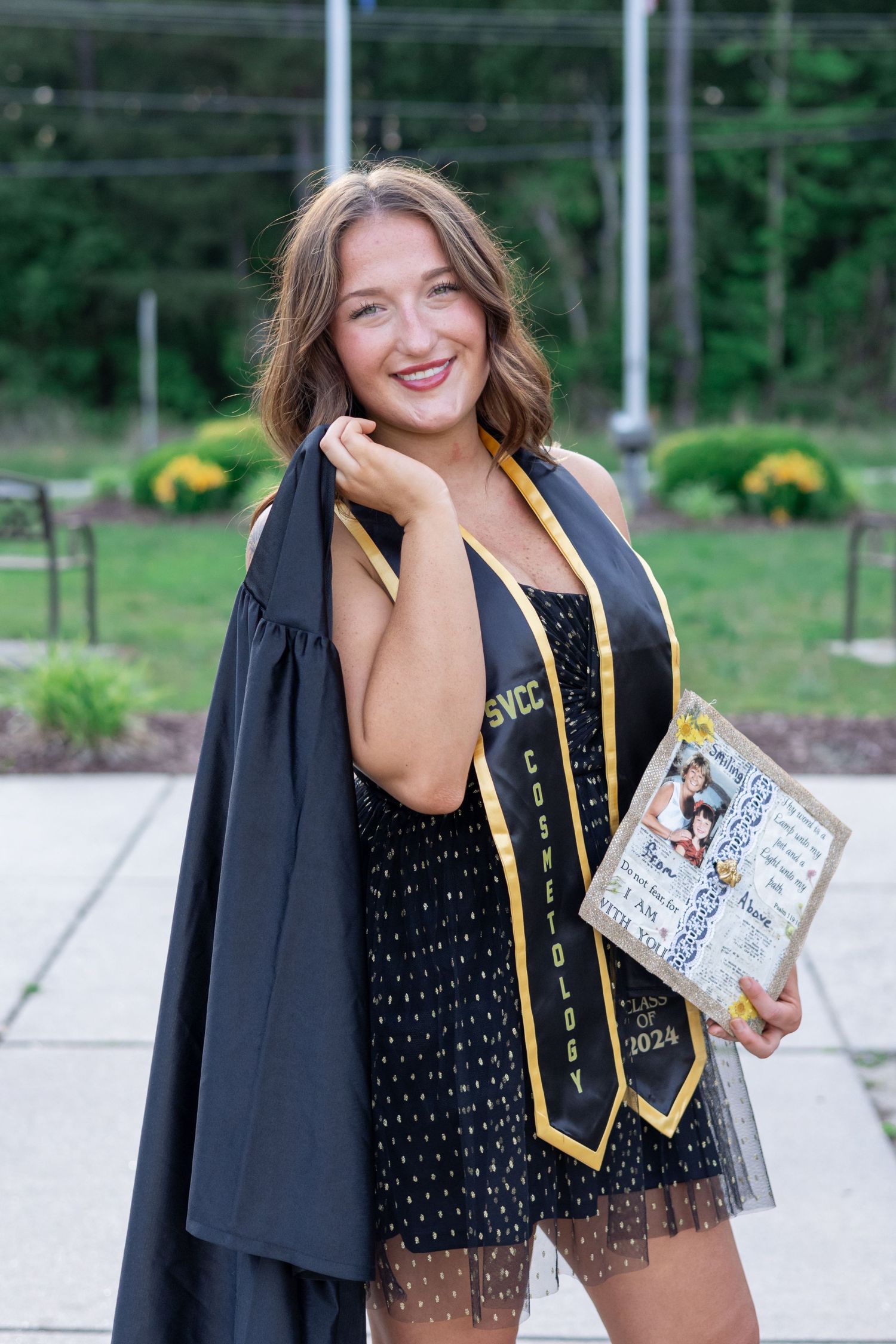 A graduation portrait featuring academic regalia and a commemorative book.