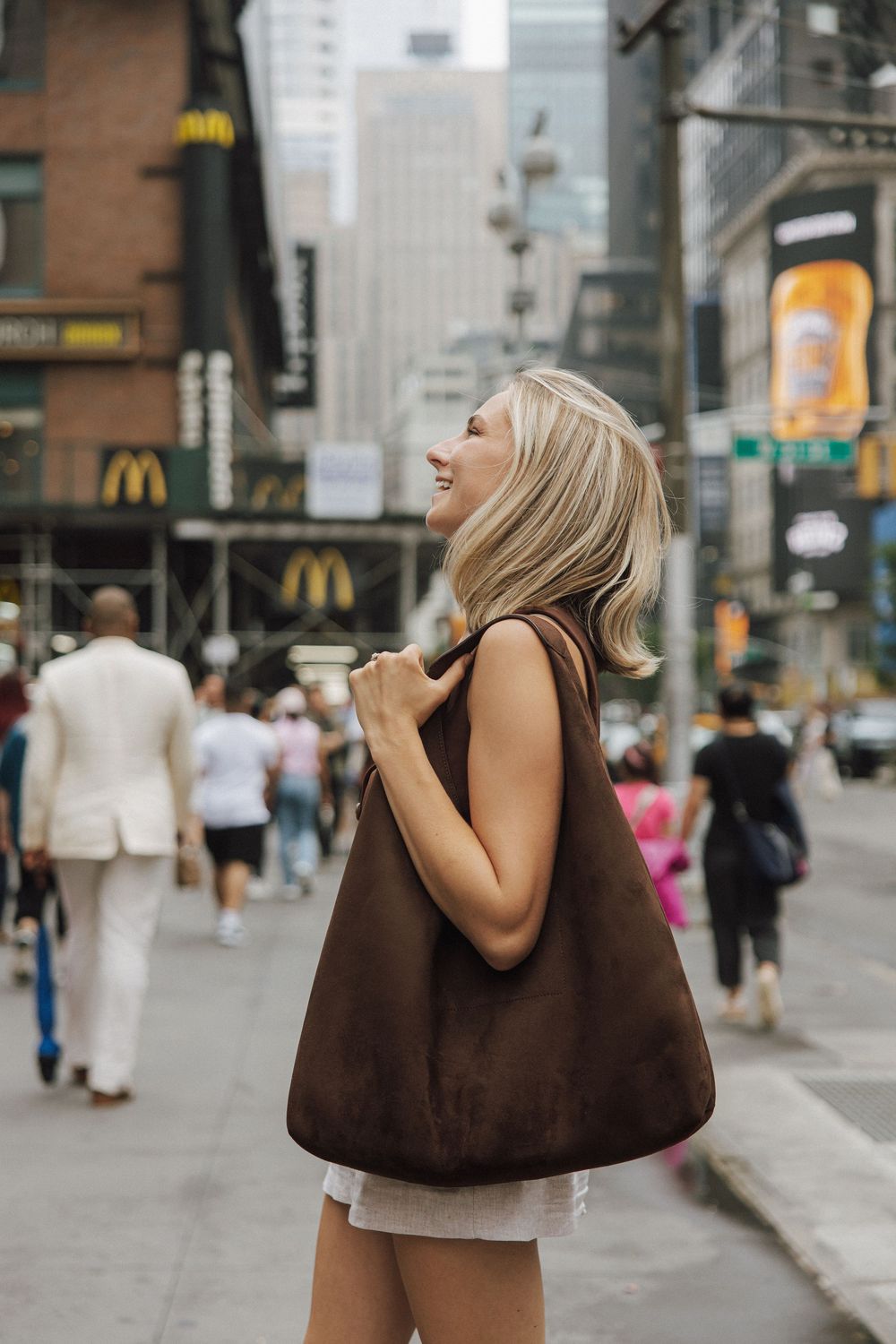 A sequence of photos showing someone carrying a brown handbag while walking down a busy city street near storefronts.