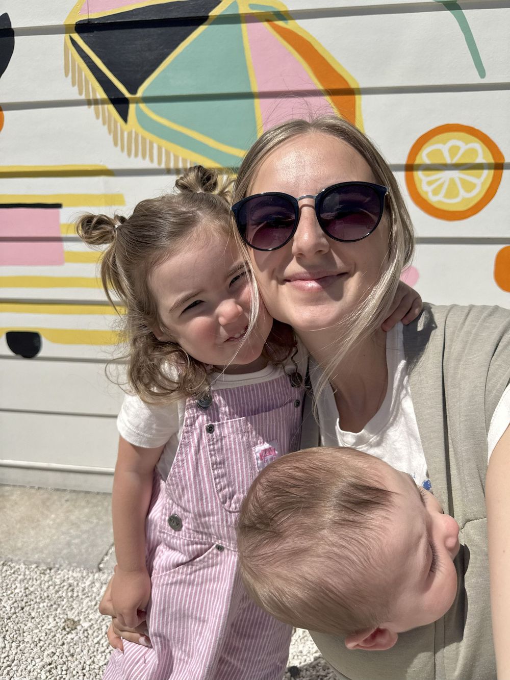 A cheerful outdoor portrait against a pastel-colored geometric wall mural.