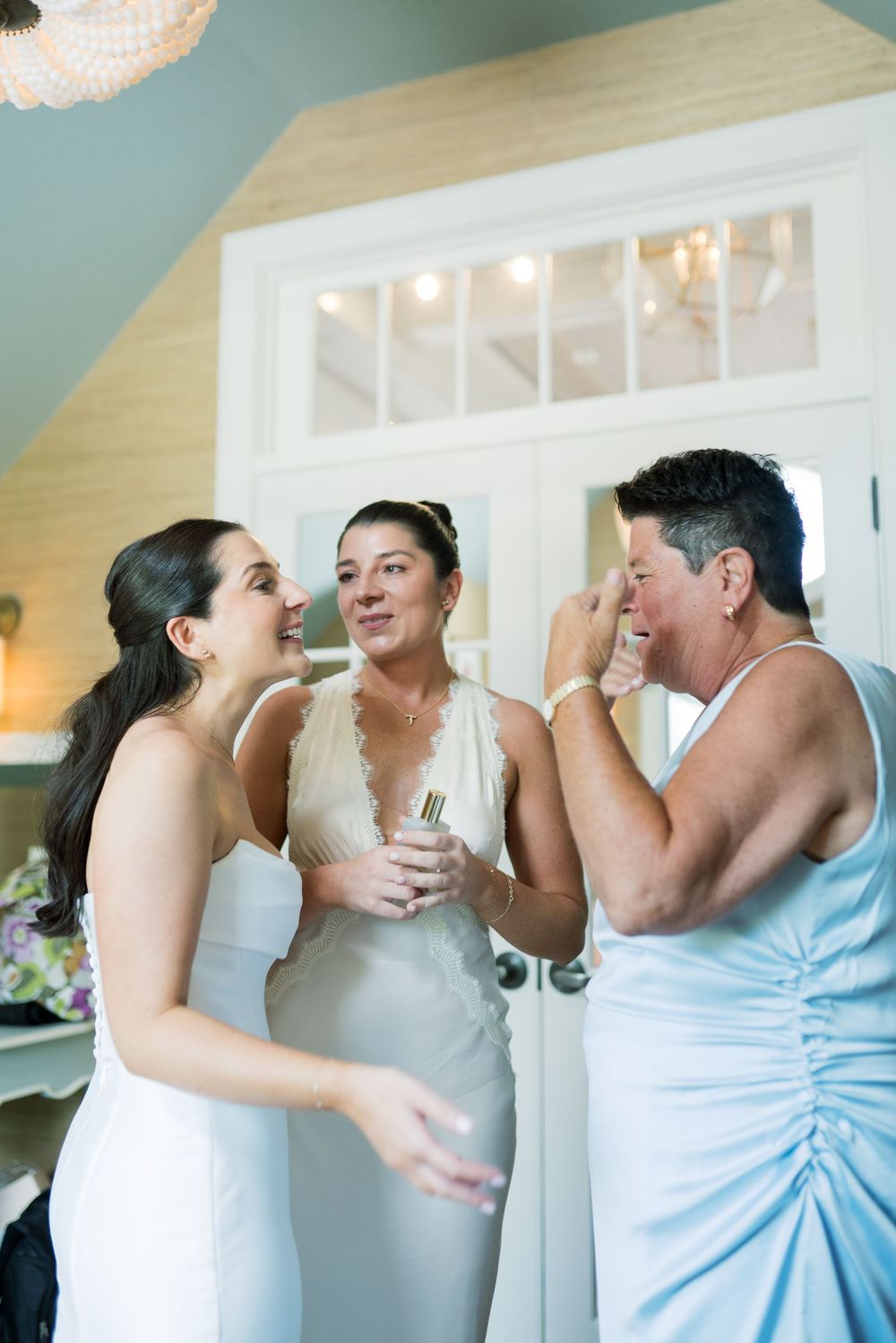 Wedding party members in light blue and white dresses share emotional moments together.