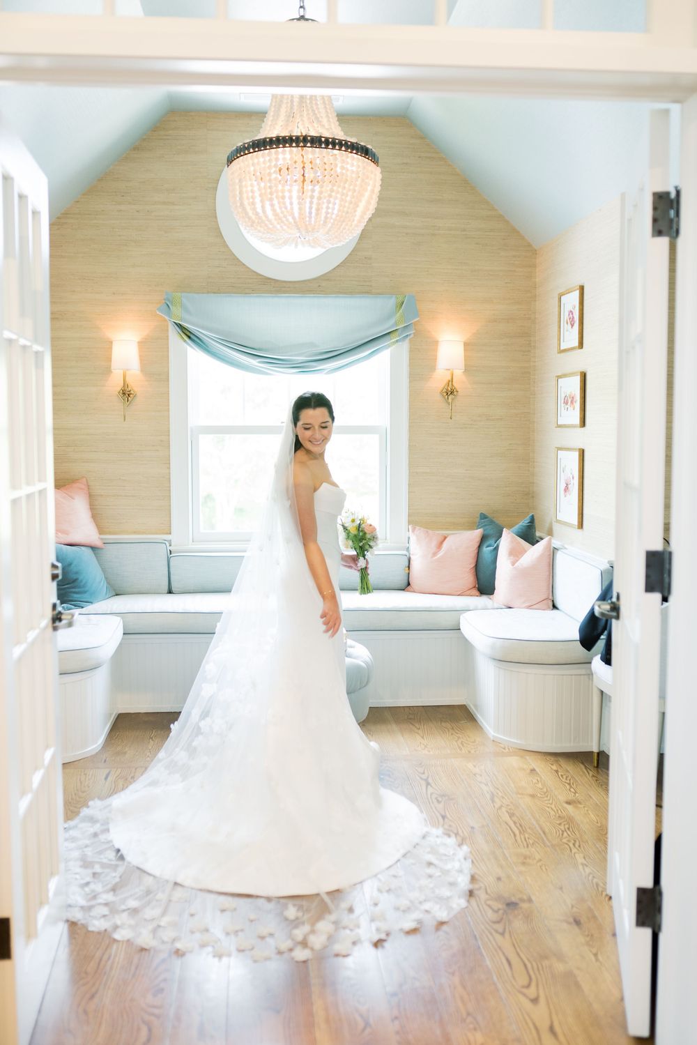 A bride spins in her white gown inside a bright room with beige walls and elegant lighting.