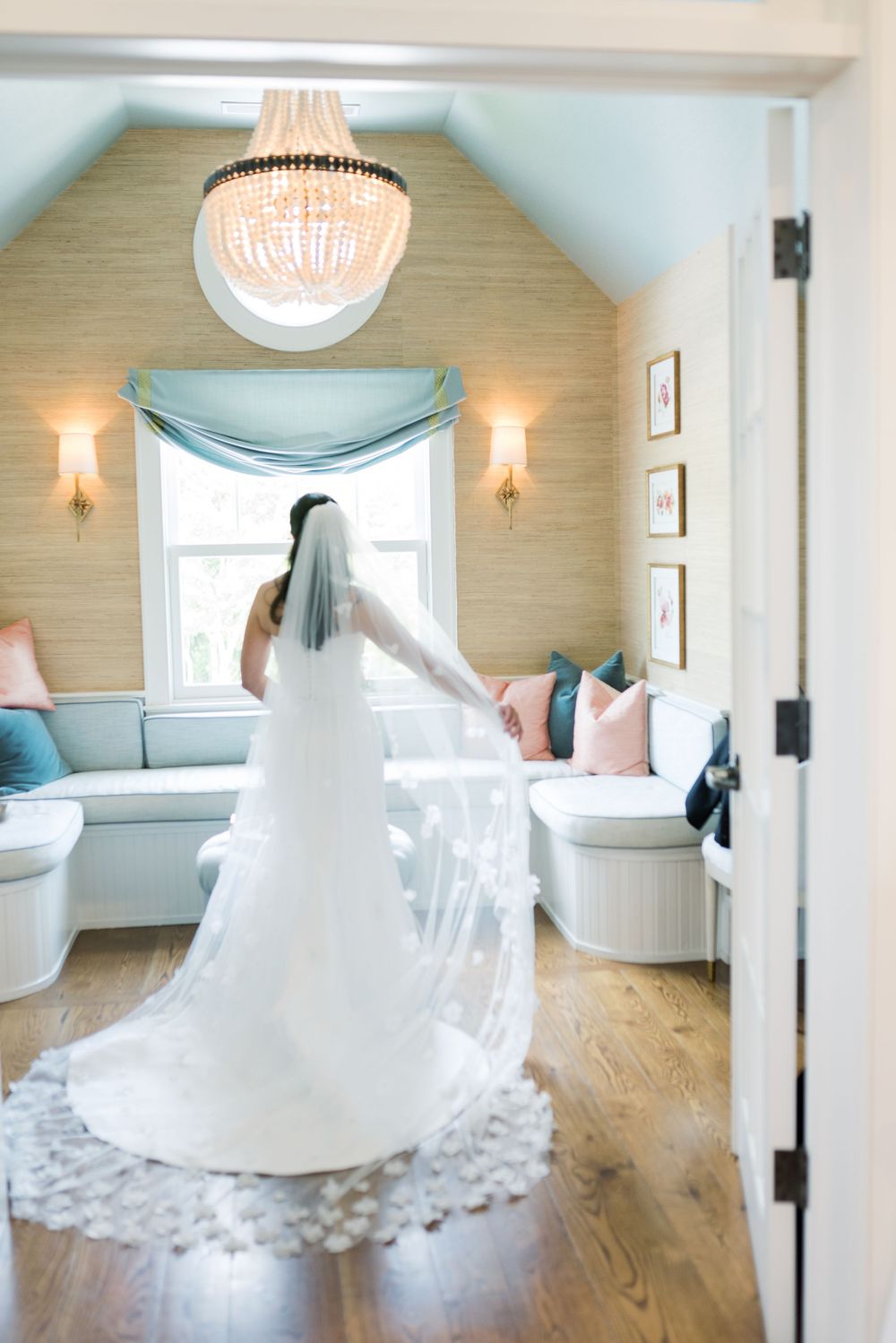 A wedding dress twirls in an elegant room with chandelier and coastal-inspired decor.