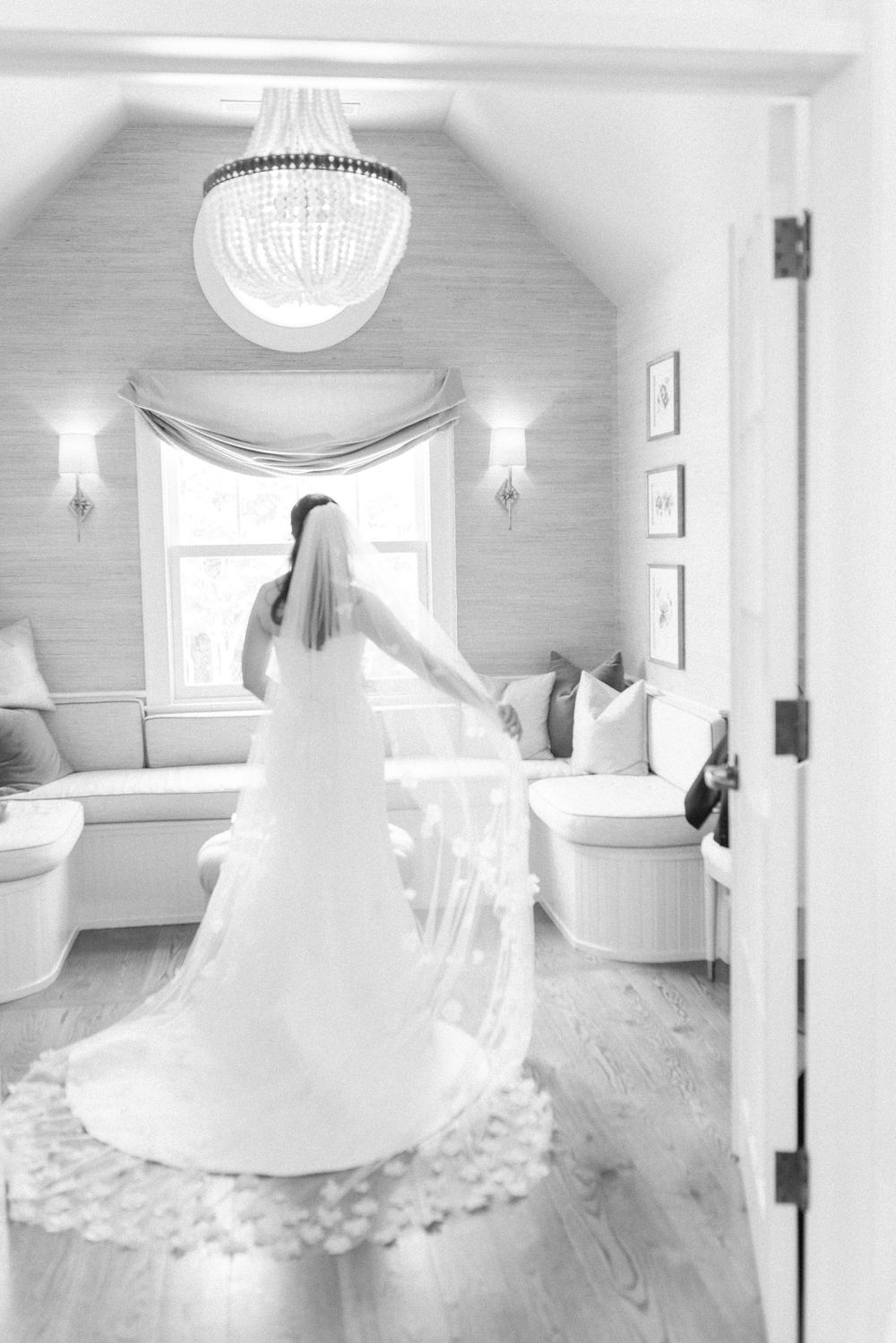 A wedding dress in motion captured in a light-filled room with hardwood floors.