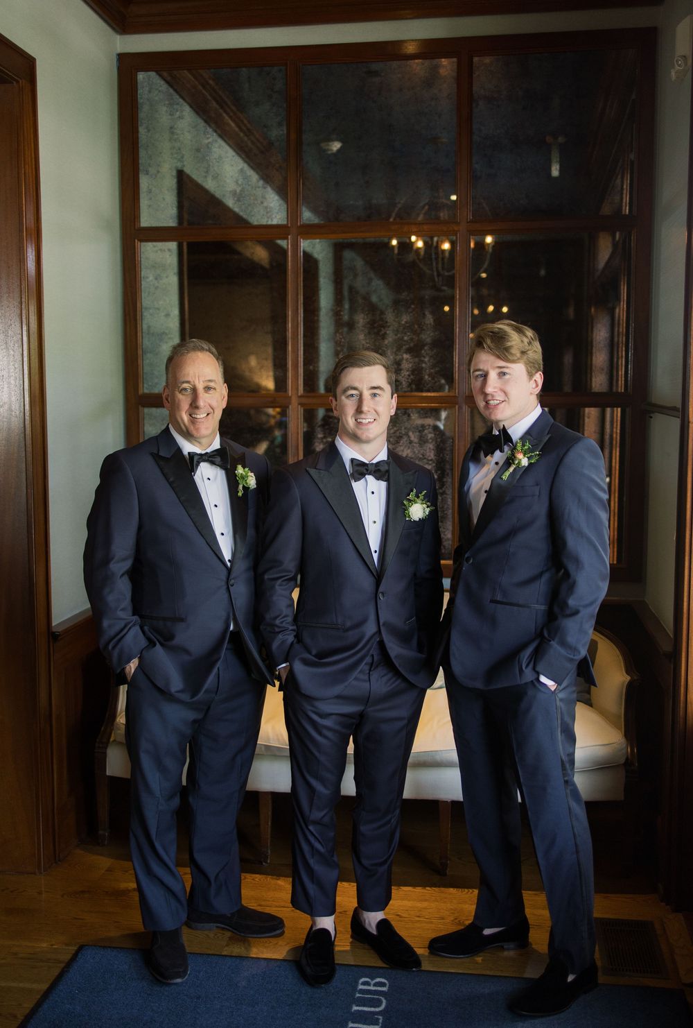 Groomsmen in navy suits pose casually in an elegant indoor setting.