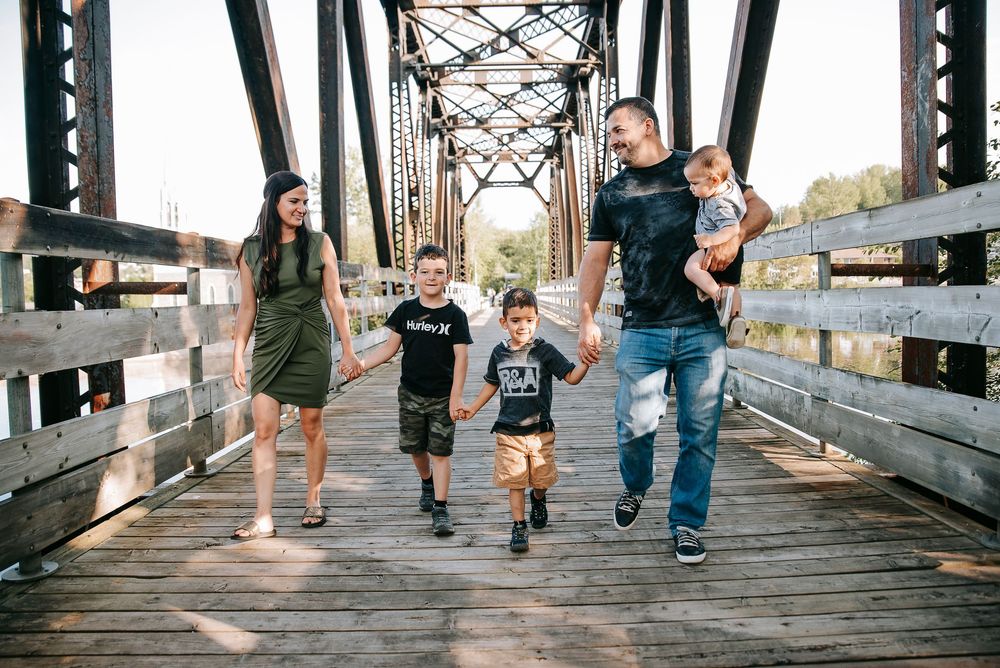 Family walking together on wooden bridge holding hands.