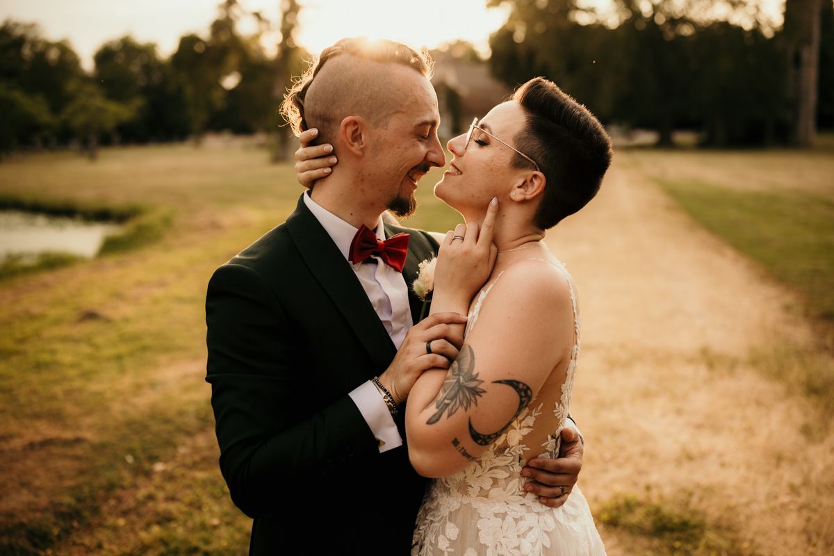 An emotional wedding moment shared between a couple on a sunny outdoor path.