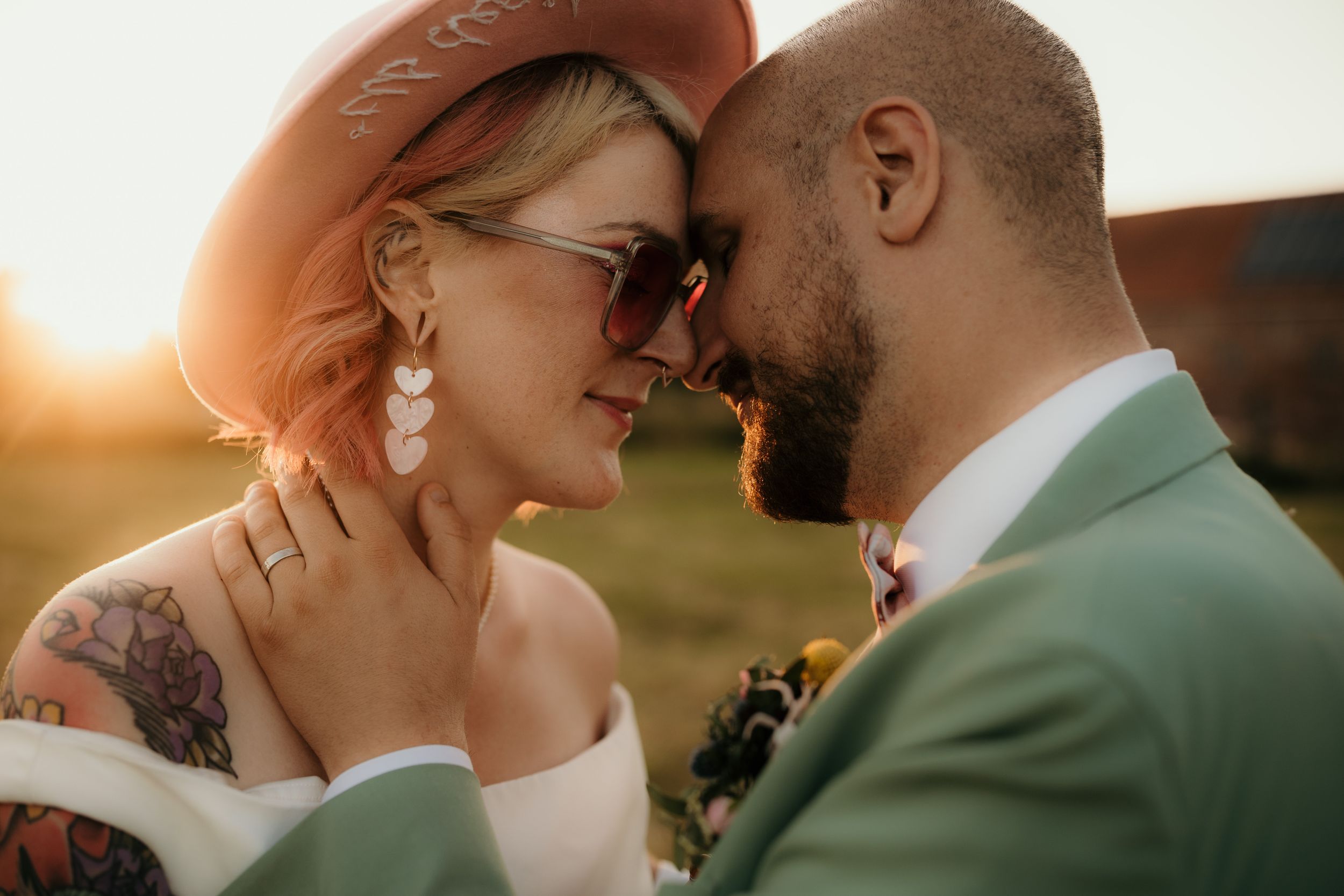 A tender romantic moment between a couple in formal wear during sunset.