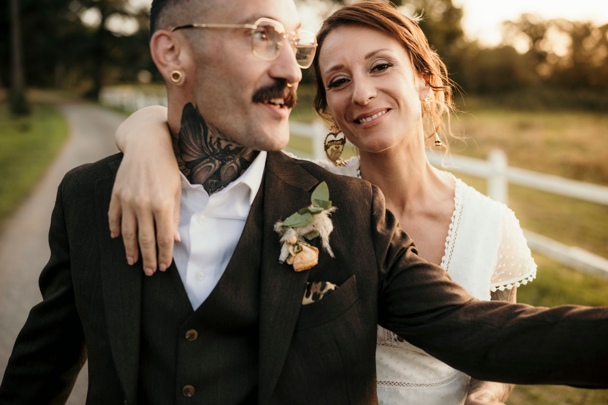 A joyful wedding couple shares a candid laughing moment outdoors.