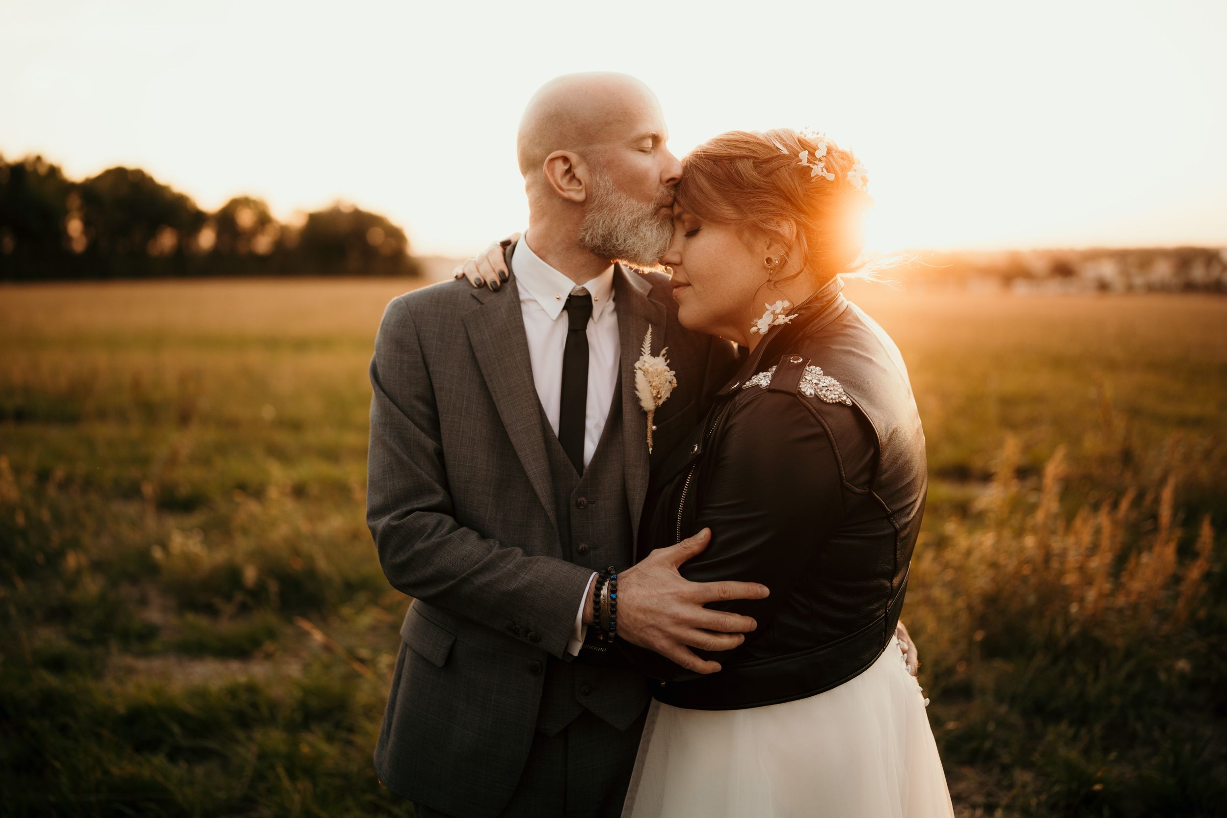 A tender embrace between a couple during golden hour in a sunlit field.