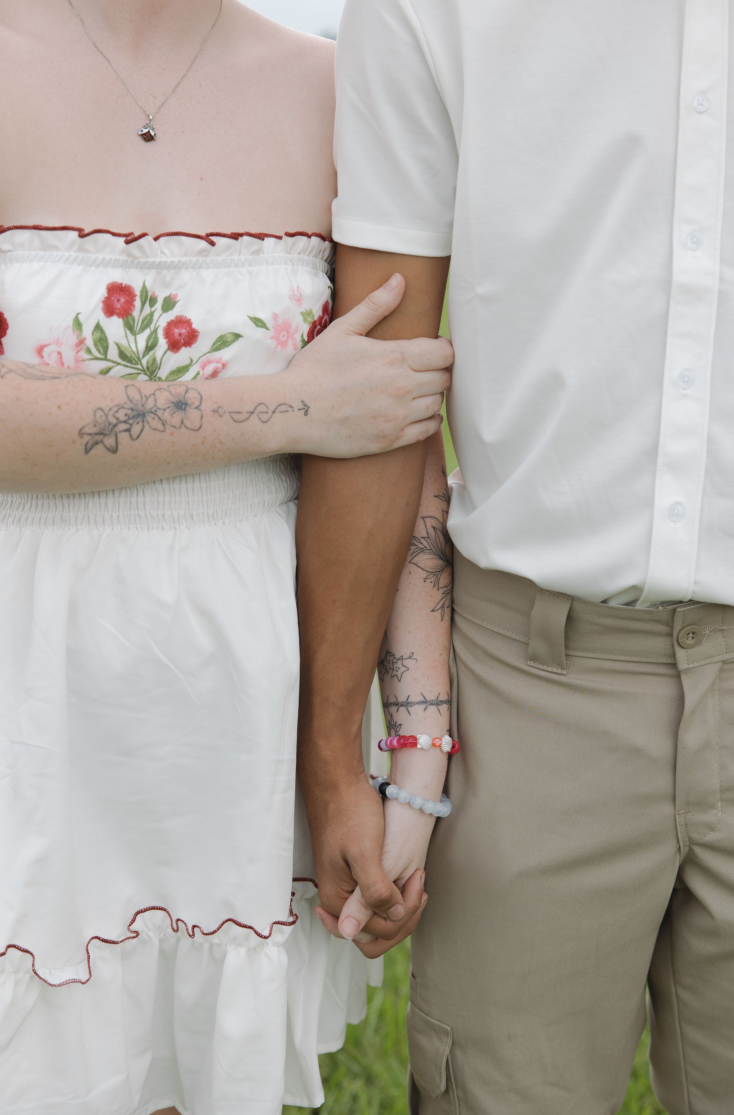 Close-up details of white dress embroidery and khaki pants in an outdoor setting.