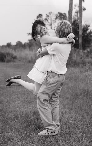 Black and white photo of a couple dancing and spinning in a grassy field.
